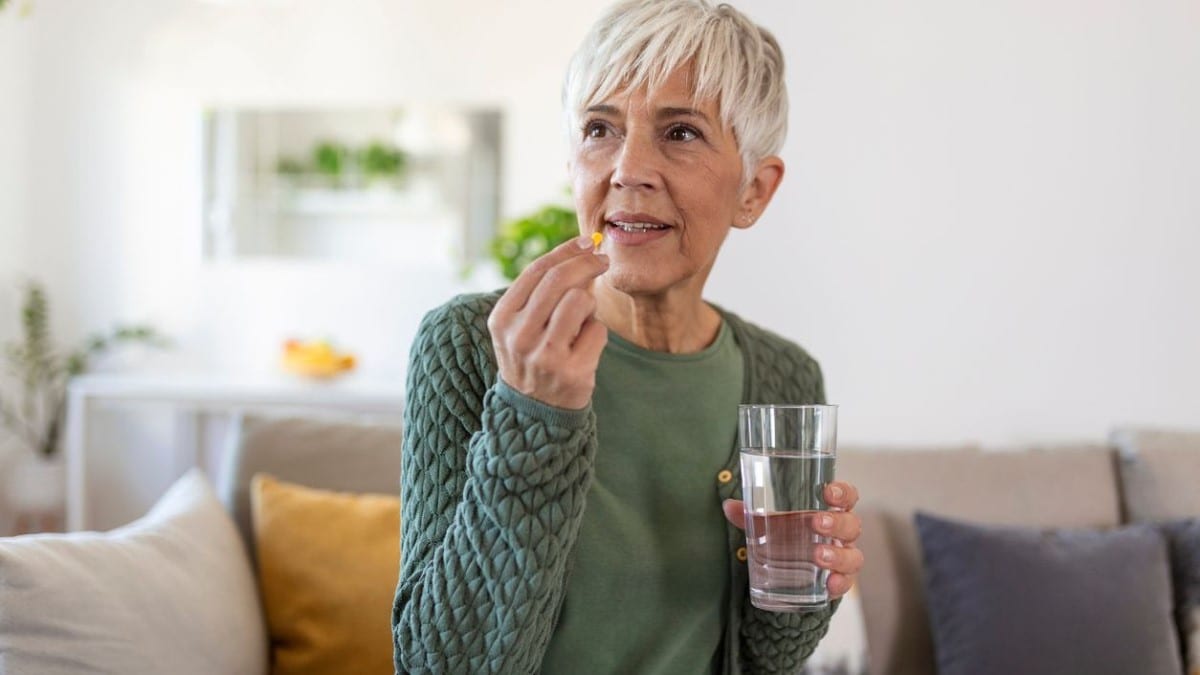 Woman taking a pill with a glass of water.