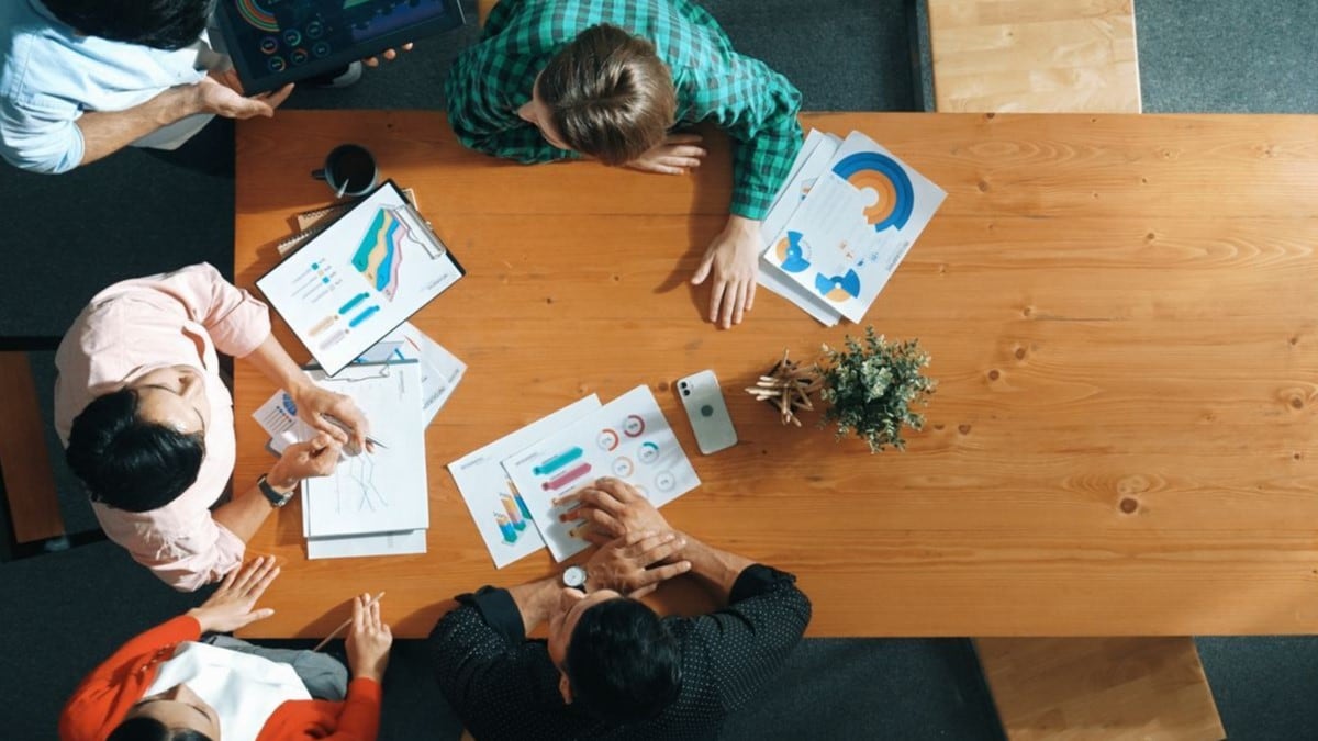 A team of five reviewing charts and graphs during a meeting.