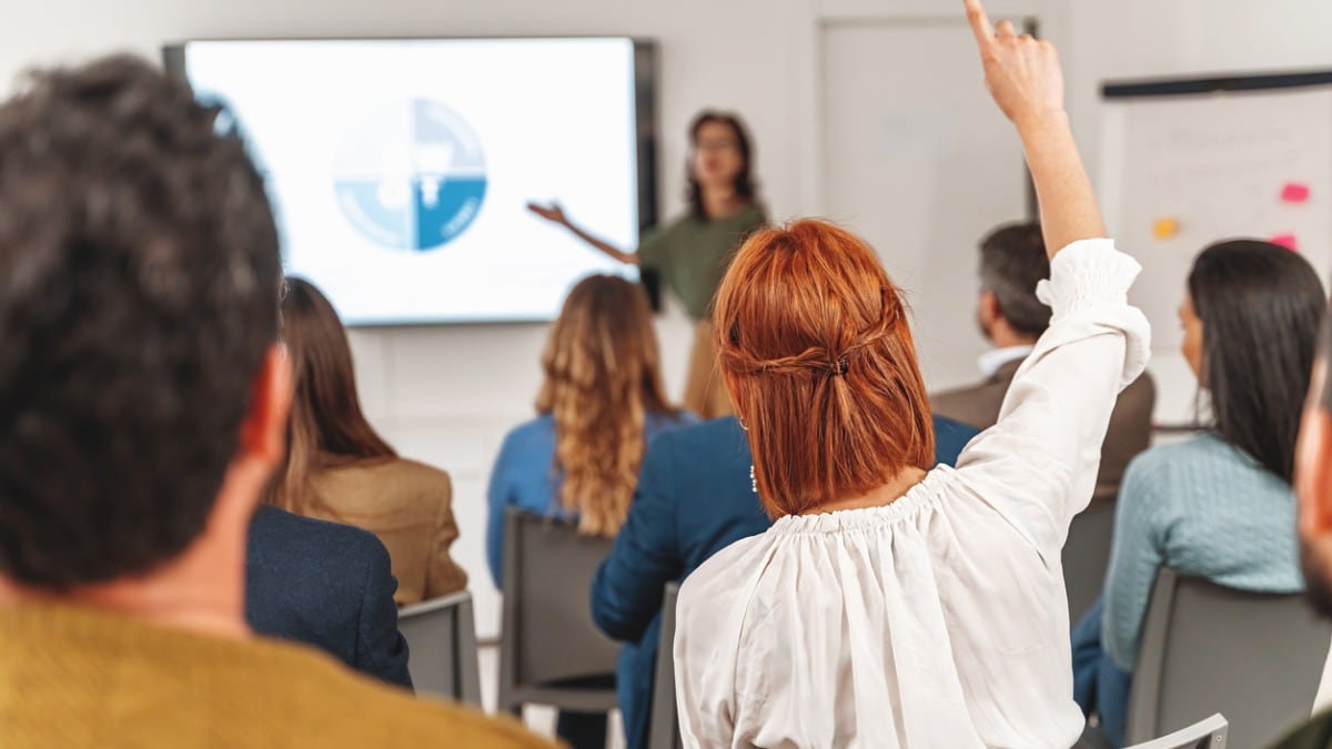 A woman raising her hand during a presentation.