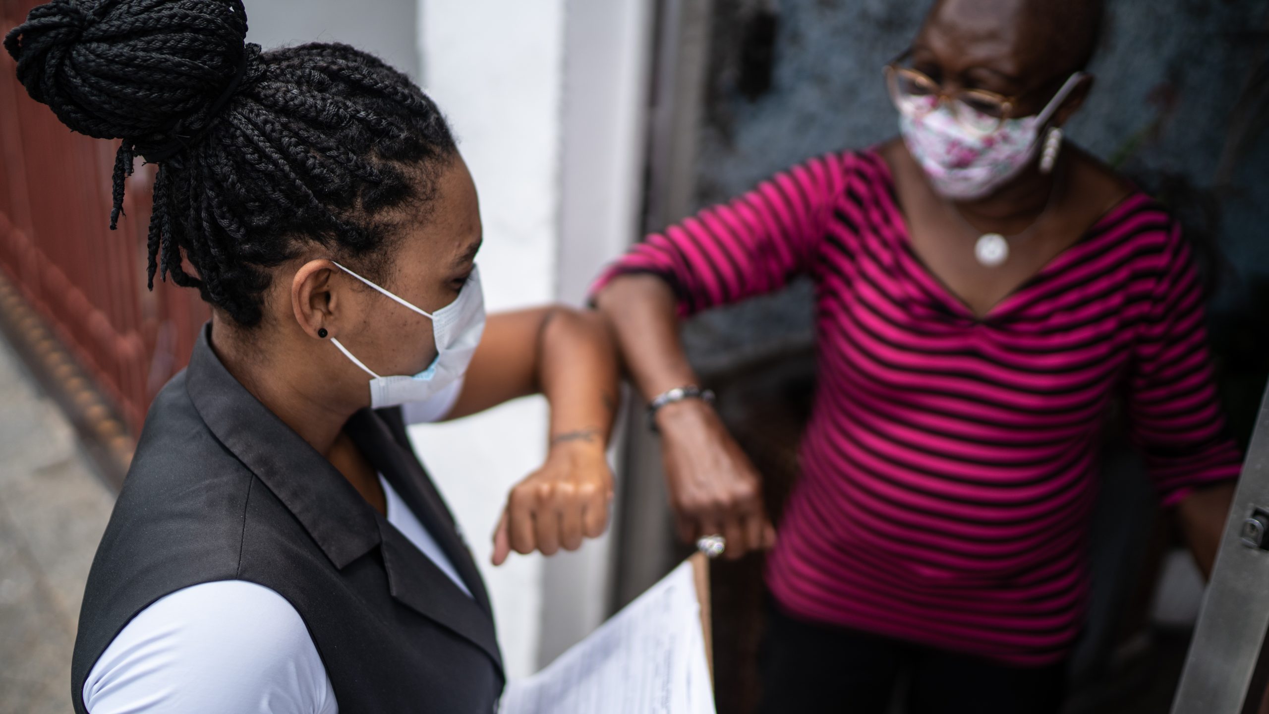 — title missing — Epidemiologist standing at a resident's door collecting health data using a survey.