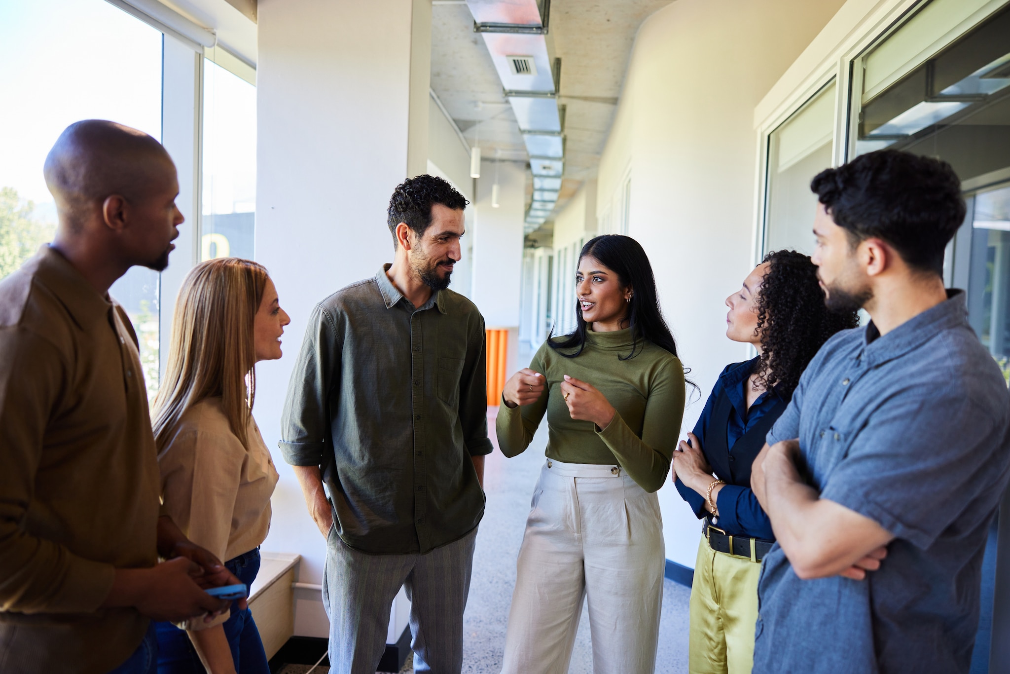 Group of diverse colleagues talking in an office hallway