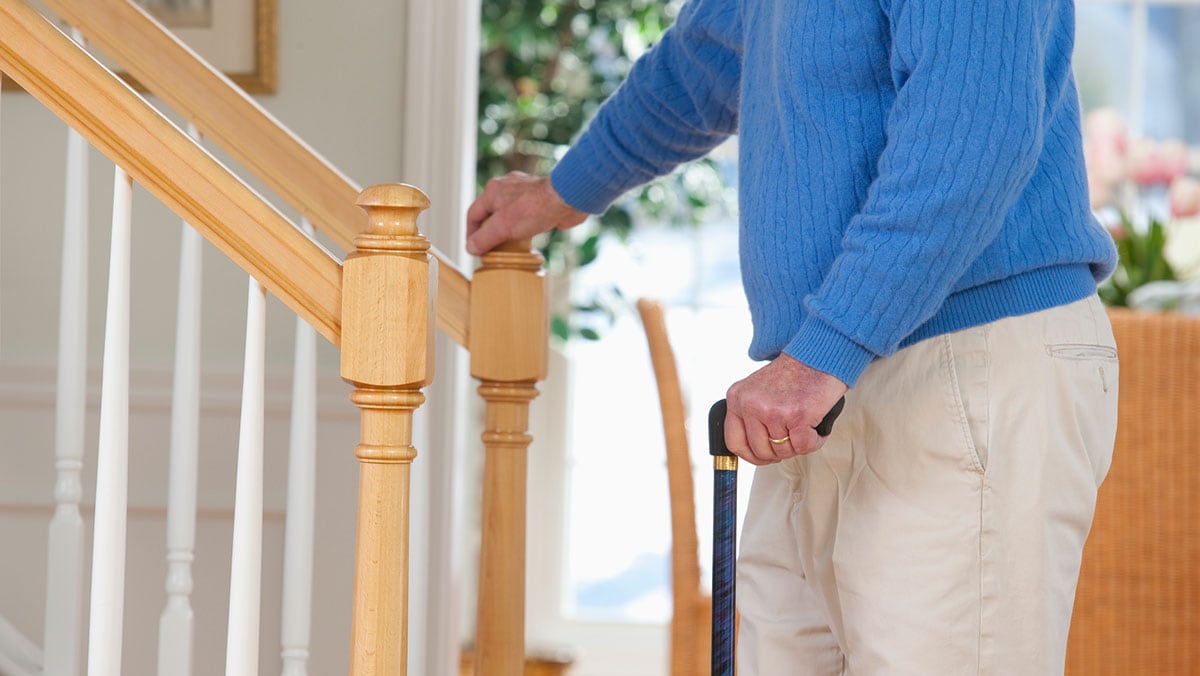 older man with a cane walking up stairs