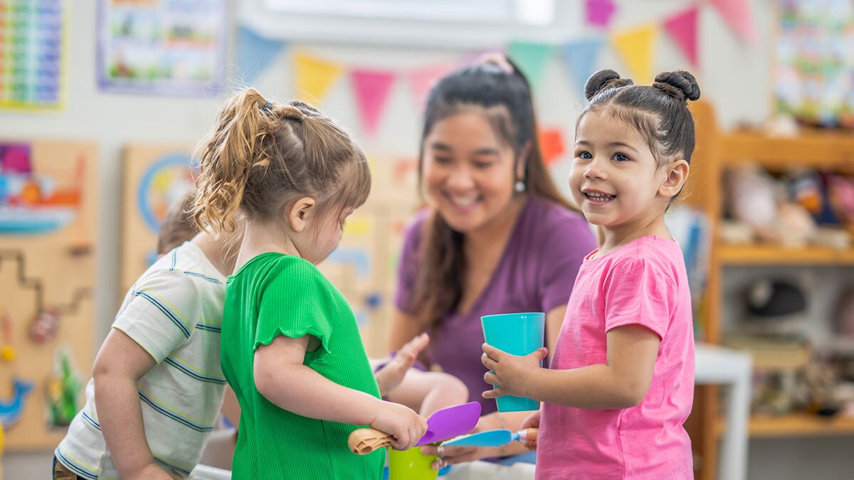 An early care provider working with children at the activity table