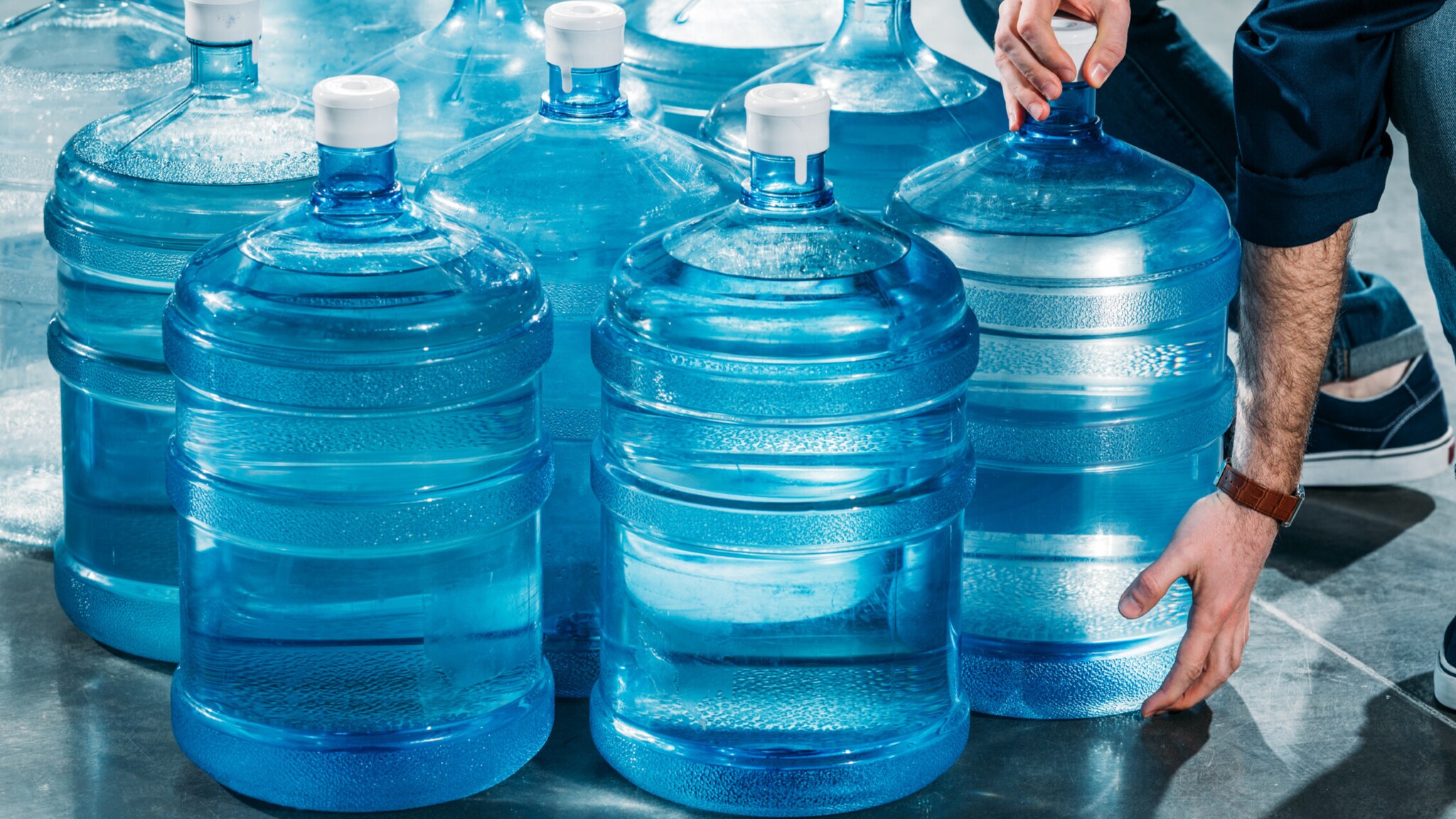 Picture of person delivering large transparent bottles with drinking water