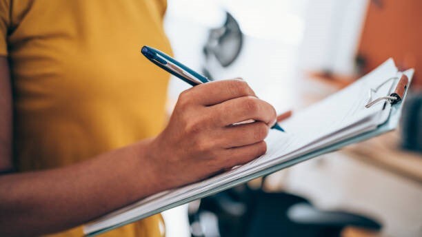 Person writing on a clipboard