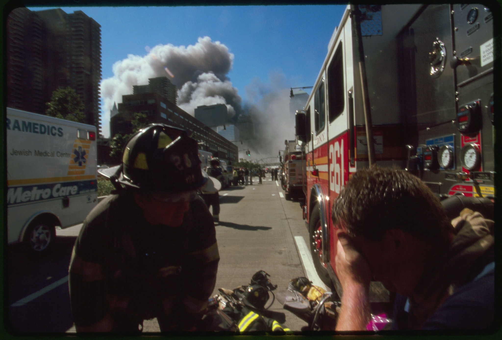 A distressed firefighter is comforted by a fellow firefighter as dust and smoke from the World Trade Center fills the air.