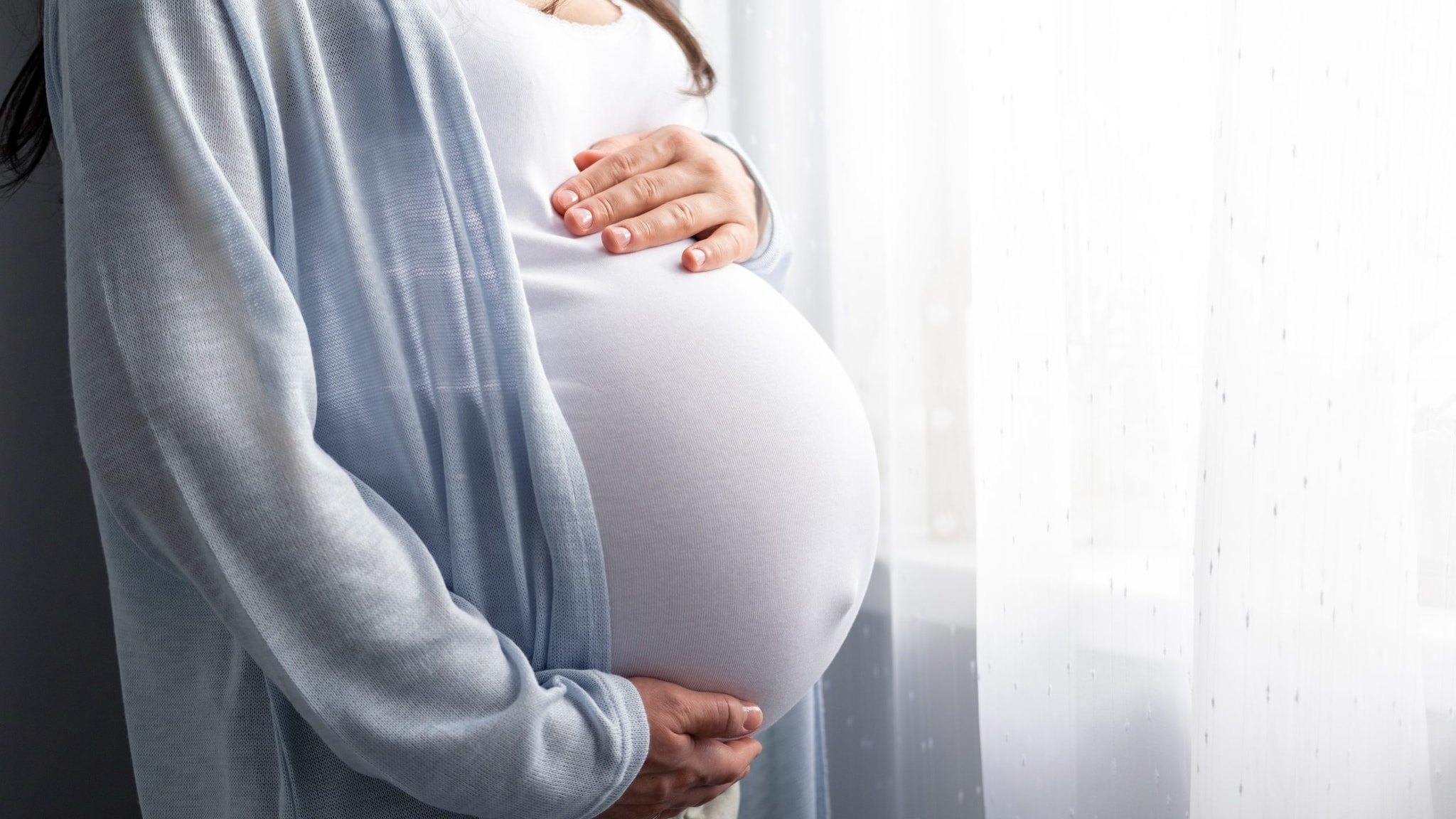 Pregnant woman with hands on their abdomen.